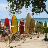 Colorful surfboards lined up on a sandy beach with ocean waves and blue sky in the background
