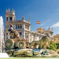 Cibeles Fountain with lion sculptures and historic architecture under a clear sky in Madrid, Spain.