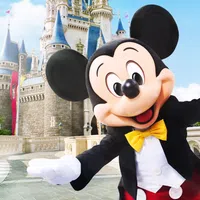 Mickey Mouse in classic attire greeting visitors in front Cinderella's castle at Walt Disney World