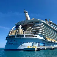 Royal Caribbean's Allure of the Seas cruise ship docked at port on a clear sunny day over blue ocean water