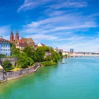 Panoramic view of Basel city with Rhine river, historic buildings, and blue sky on a sunny day.