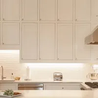 Bright modern kitchen with white cabinetry, stainless steel appliances, and under-cabinet lighting.