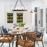 Bright dining room with wooden table, cushioned chairs, wall planters, and modern chandelier with glass lights.
