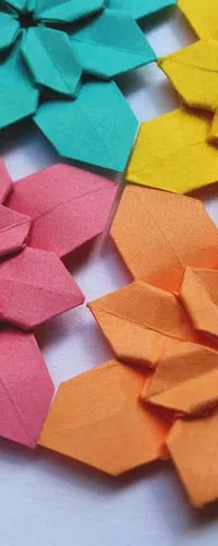 Close-up of colorful origami flowers in pink, orange, teal, and yellow on a white background.
