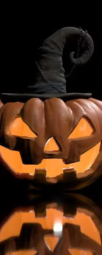 Glowing jack-o'-lantern with a crooked witch hat reflecting on a black surface for Halloween.