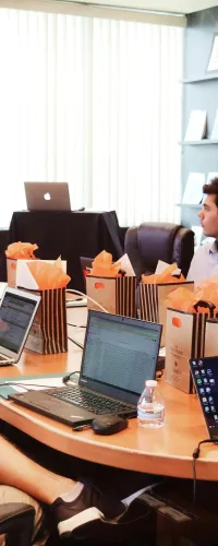 a group of people sitting around a table with laptops