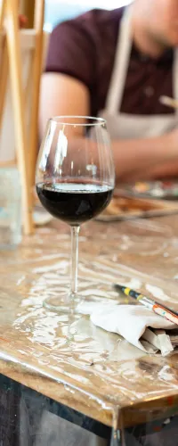 a group of people sitting at a table with a laptop and a glass of wine