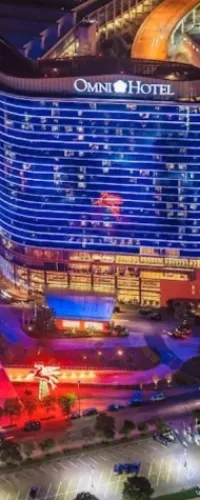Night view of Omni Hotel illuminated with blue and red lights alongside a parking lot and surrounding streets.