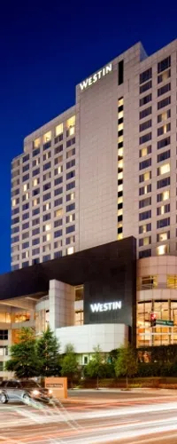 Night view of the illuminated Westin hotel building with cars and light trails on the street below.