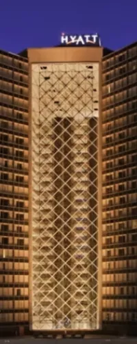 Hyatt hotel building at night with illuminated balcony lights and geometric facade design under a dark sky