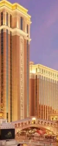 Venetian tower and illuminated building facade at dusk with canal and bridge in Las Vegas