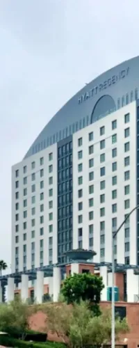 Modern Hyatt Regency hotel building with white facade and numerous windows under a cloudy sky