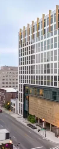 Modern urban street view with high-rise glass and metal buildings along a quiet city road.