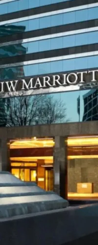 Exterior of JW Marriott hotel building with reflective glass windows and illuminated entrance at dusk