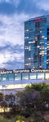 Metro Toronto Convention Centre building at dusk with illuminated windows and cloudy sky in the background