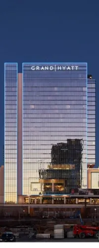 Grand Hyatt hotel building with reflective glass facade at dusk, capturing urban cityscape and construction area below.