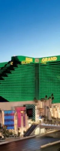 Green MGM Grand hotel and casino tower with bright signs under clear blue sky in Las Vegas.