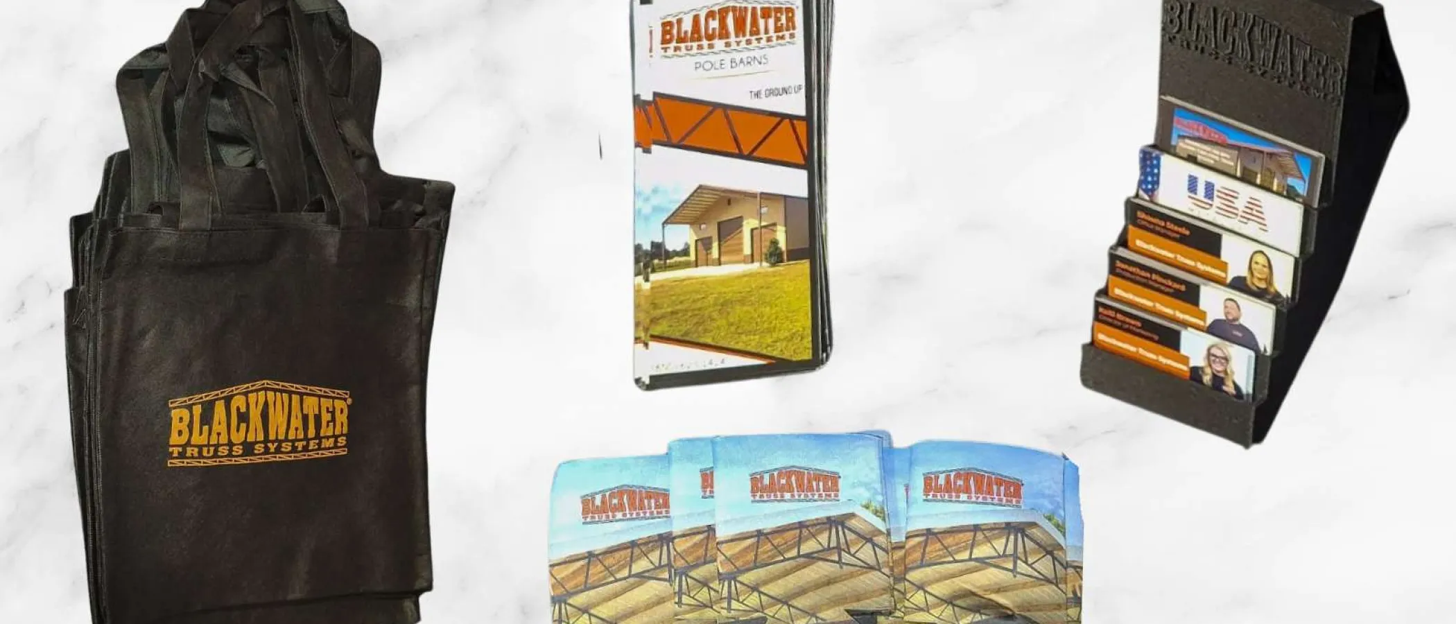 Blackwater Truss Systems branded tote bags, brochures, business cards, and drink koozies on a marble surface.