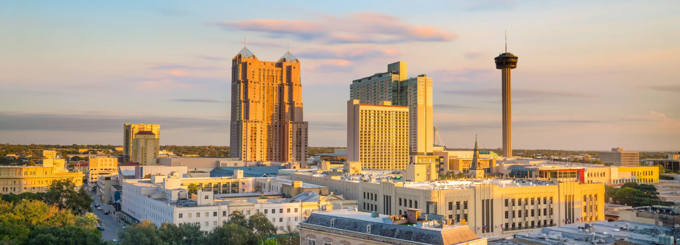 Panoramic view of San Antonio skyline at sunset, highlighting modern buildings and historical architecture.