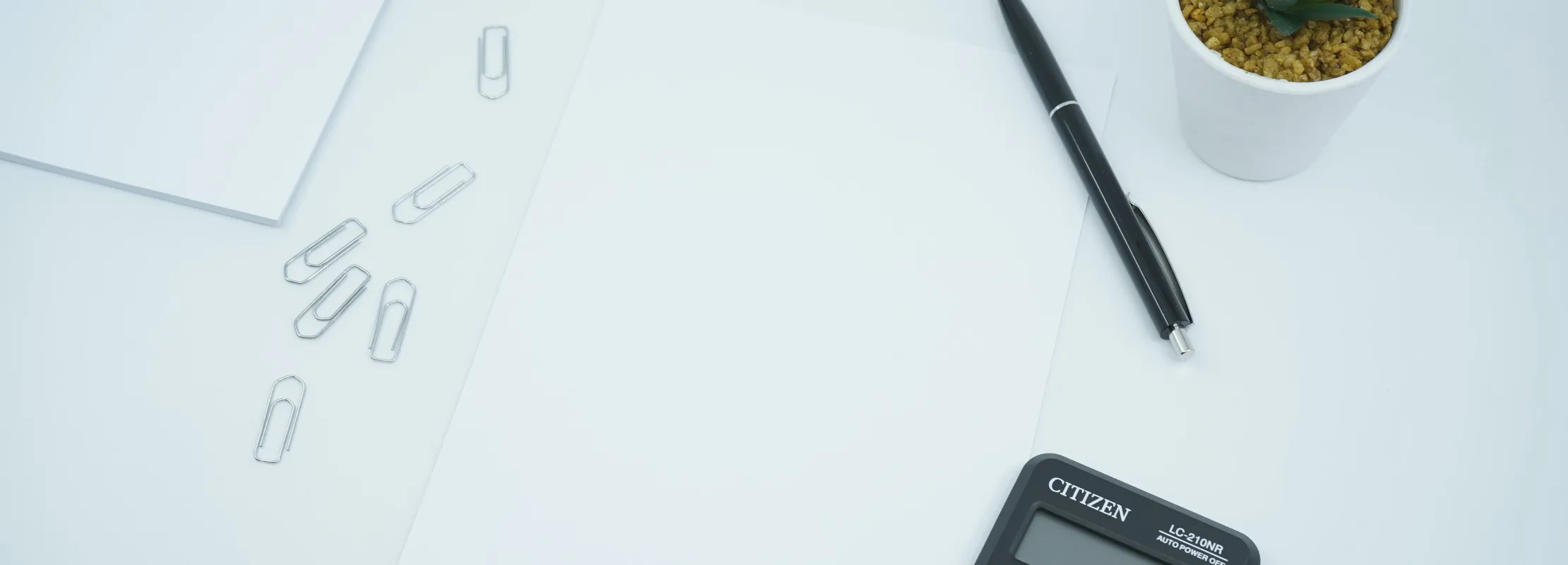 a calculator and a plant on a white surface