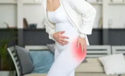 Woman in white outfit holding hip in pain, highlighted red area indicating hip discomfort or injury.