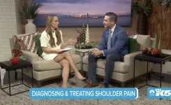 Two hosts discuss diagnosing and treating shoulder pain on a cozy TV set with holiday decor and cityscape backdrop.