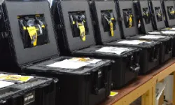 Thumbnail control image for Row of open black cases with electronic equipment and yellow tags on a workshop table
