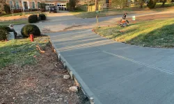 Thumbnail control image for Freshly poured concrete driveway with a worker finishing the surface on a residential street.