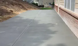 Thumbnail control image for Freshly poured concrete driveway beside a house, surrounded by trees and residential buildings.