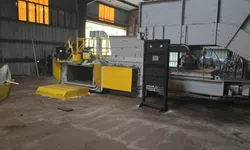 Thumbnail control image for Industrial machinery with yellow panels inside a large factory with high ceilings and orange windows.