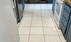 Thumbnail control image for Narrow kitchen with white tiled floor, blue cabinets, wooden countertops, white stove, and wooden cabinet at the end.