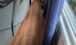 Thumbnail control image for Narrow space between couch and window with wood floor, blue curtains, and visible vent on floor.