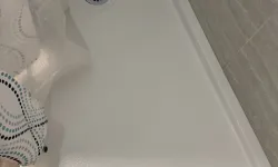 Thumbnail control image for White textured shower floor with drain, beige tiled walls, and patterned shower curtain partially visible.