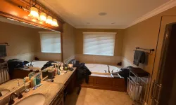Thumbnail control image for Spacious bathroom with large mirror, double sink, soaking tub, and beige tile floor under warm lighting.