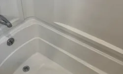 Thumbnail control image for Clean white bathtub with silver drain and faucet in a minimalist bathroom setting.