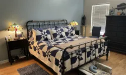 Thumbnail control image for Cozy bedroom with metal bed frame, blue and white quilt, stained glass lamps, dark dresser, and hardwood floor cleaned by MaidPro
