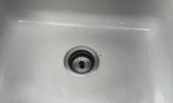 Thumbnail control image for White kitchen sink with metal faucet and drain, orange sponge on the side, and stainless steel countertop.