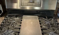 Thumbnail control image for Modern stainless steel gas stove with four burners and central griddle in clean kitchen setting.