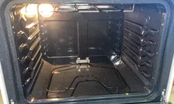 Thumbnail control image for Interior view of a clean empty electric oven with visible heating element and oven light on.