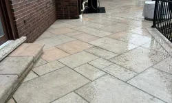 Thumbnail control image for Wet stone tiled patio next to a brick house with a barbecue grill and outdoor furniture.