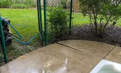 Thumbnail control image for Wet patio with concrete slabs next to a white tub and green chain link fence near a blooming lilac bush.