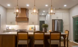 Thumbnail control image for Modern kitchen with wooden island, woven back chairs, pendant lights, stainless steel fridge, and white cabinets.