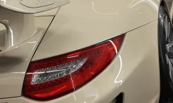 Thumbnail control image for Close-up of the rear side and spoiler of a cream-colored sports car with red taillight and 3.8 badge