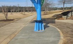 Thumbnail control image for Blue metal support structure with caution sign on a paved path in a park on a clear day.