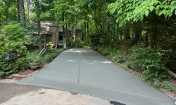 Thumbnail control image for Newly poured concrete driveway surrounded by lush green trees leading to a house in a wooded area.