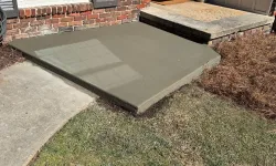 Thumbnail control image for Freshly poured smooth concrete slab next to brick house exterior and front door entry on a sunny day