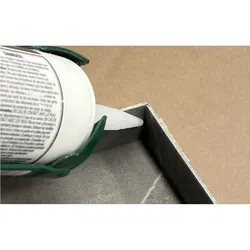Applying white sealant or adhesive from a caulking gun onto the corner of a metal or concrete surface.