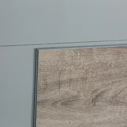 Close-up of a wooden floor panel placed on a gray concrete floor showing texture and grain details.