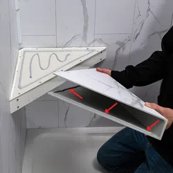 Man installing a triangular marble-patterned shelf with adhesive in a bathroom corner with tiled walls.