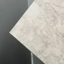 Close-up of a textured light gray tile with subtle patterns against a dark matte background.